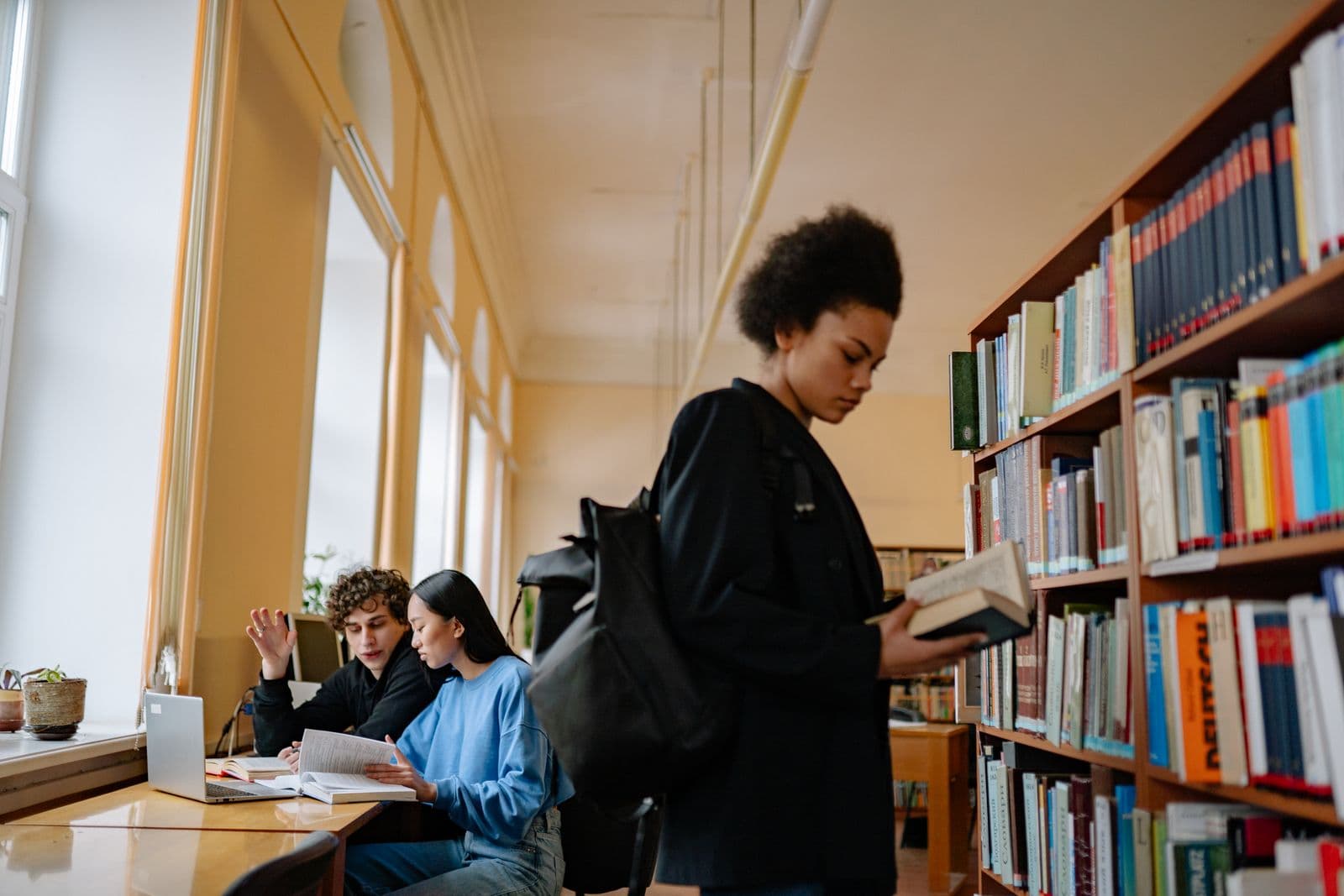Students discussing a book together in a library
