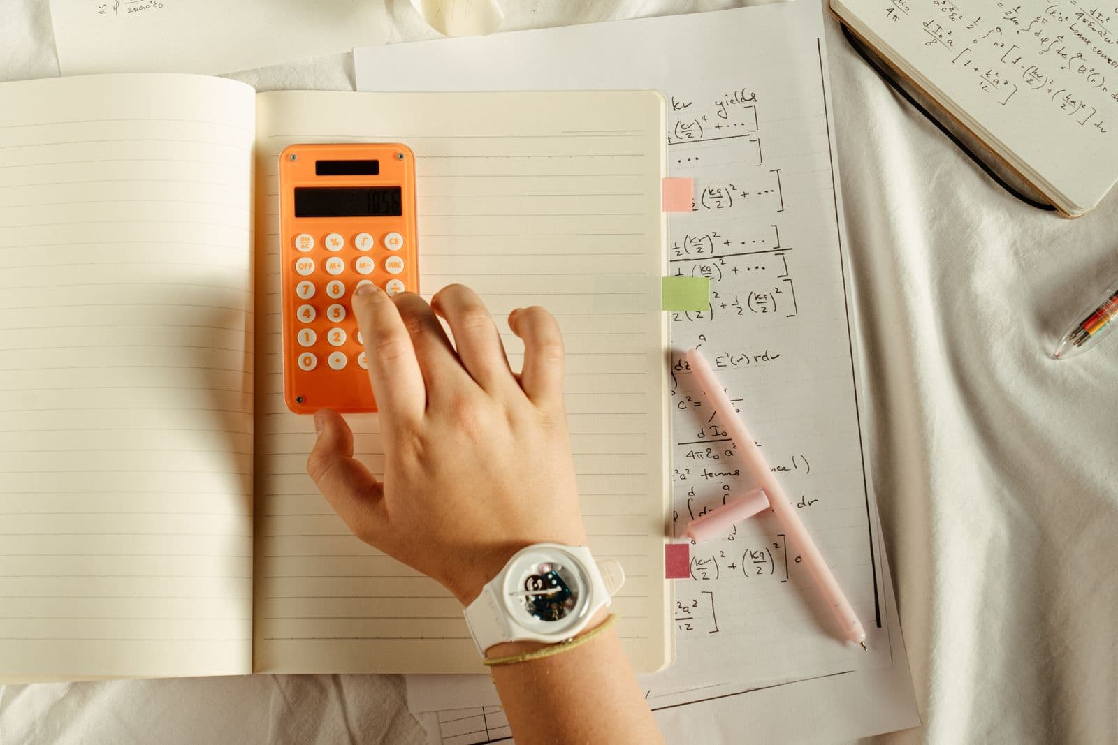 A calculator and handwritten mathematics practice on a study desk